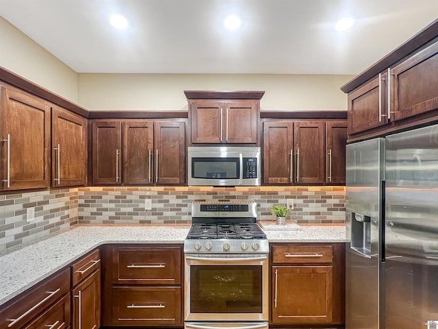 kitchen featuring tasteful backsplash, light stone countertops, and appliances with stainless steel finishes