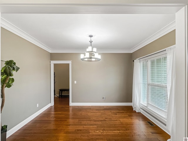 spare room with crown molding, dark wood-type flooring, and a chandelier