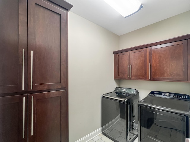 clothes washing area with cabinets, washing machine and dryer, and light tile patterned floors