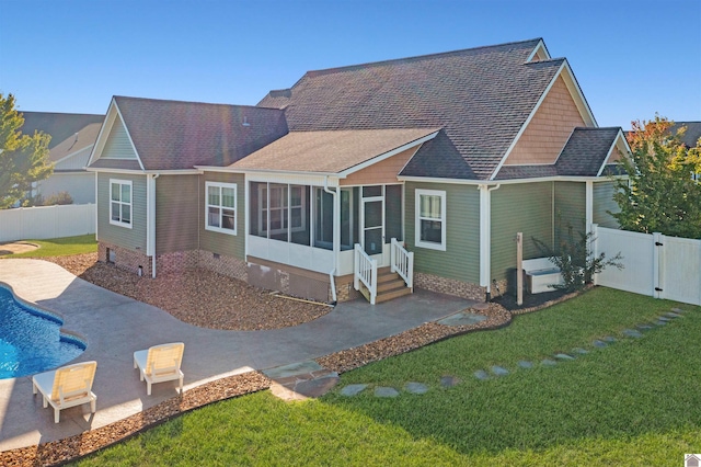 rear view of house featuring a lawn, a sunroom, a patio, and a fenced in pool