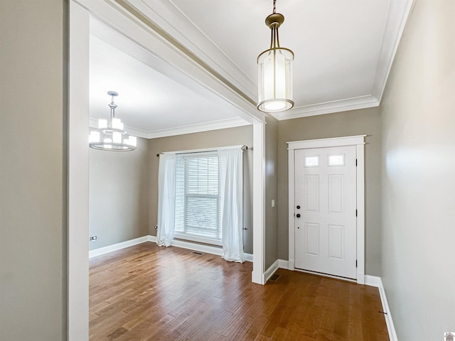 entrance foyer featuring hardwood / wood-style flooring, crown molding, and a chandelier