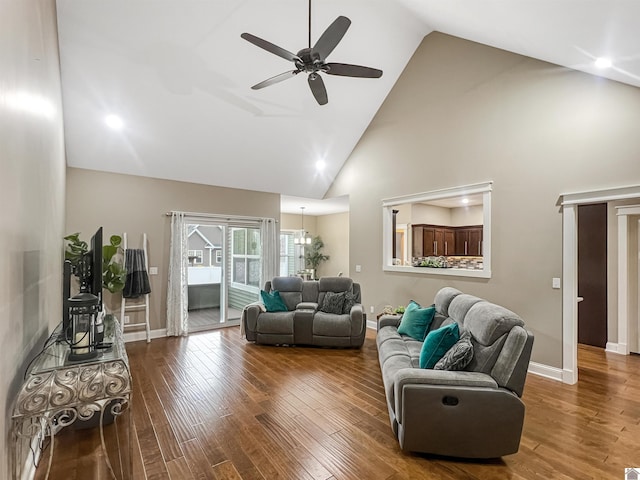 living room with ceiling fan with notable chandelier, hardwood / wood-style flooring, and high vaulted ceiling