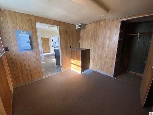 interior space featuring electric panel, dark carpet, and wood walls