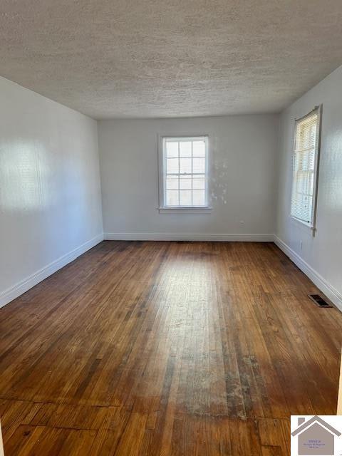 spare room with a textured ceiling and dark hardwood / wood-style floors