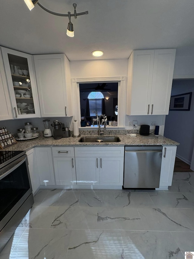 kitchen with white cabinetry, sink, stainless steel appliances, and light stone counters