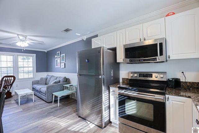 kitchen with white cabinets, appliances with stainless steel finishes, light hardwood / wood-style flooring, and ornamental molding