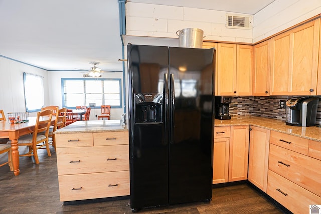 kitchen featuring black refrigerator with ice dispenser, dark hardwood / wood-style floors, light stone countertops, light brown cabinetry, and tasteful backsplash