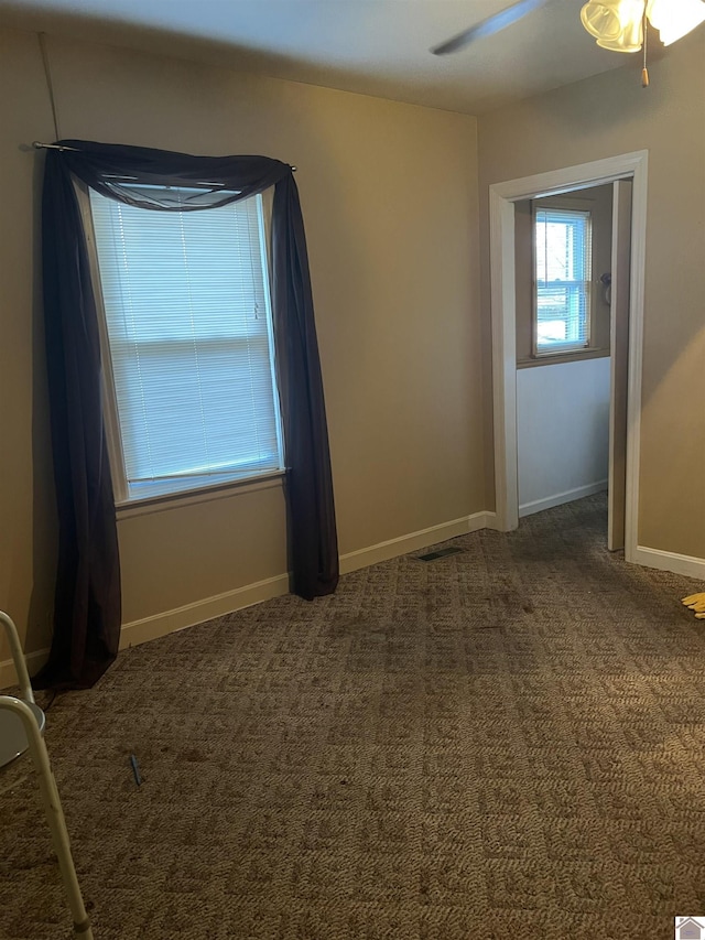 unfurnished room with dark colored carpet and ceiling fan