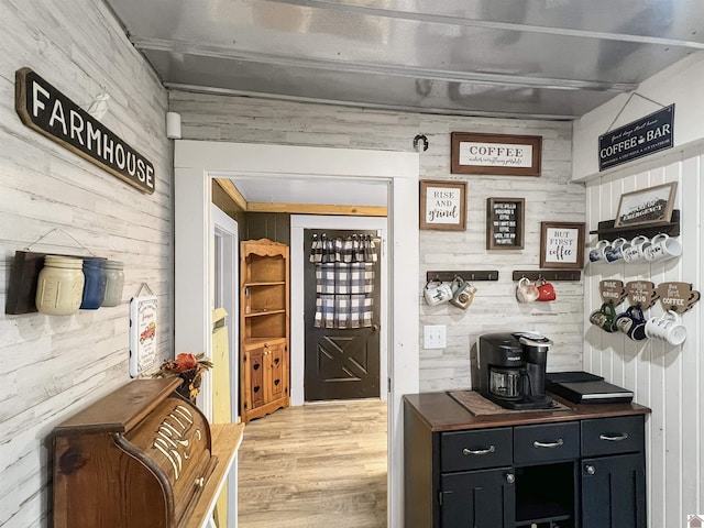 bar with light wood-type flooring and wood walls