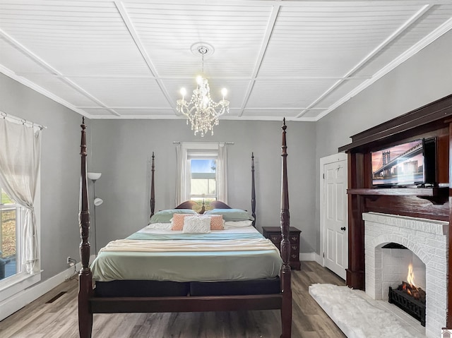 bedroom with multiple windows, a brick fireplace, and hardwood / wood-style flooring