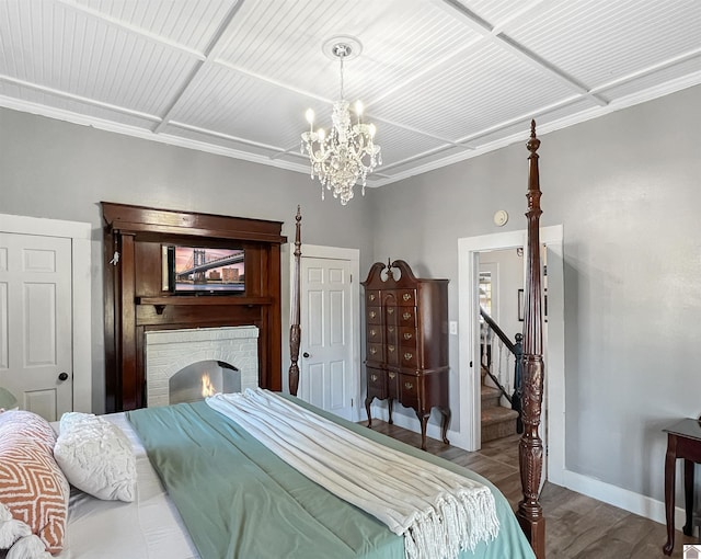 bedroom featuring a fireplace, hardwood / wood-style floors, a chandelier, and ornamental molding