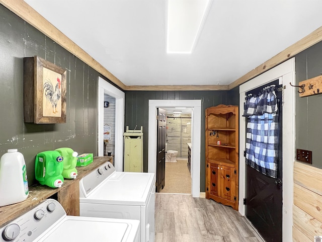 laundry room featuring washing machine and dryer, wooden walls, and light hardwood / wood-style floors