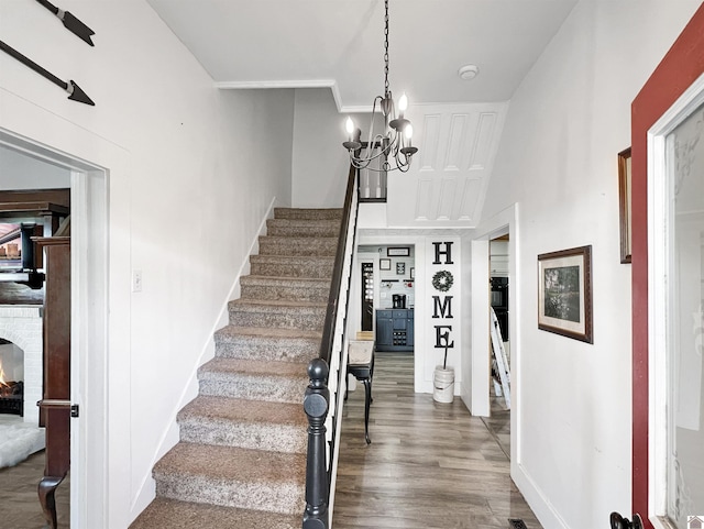 stairway with a towering ceiling, wood-type flooring, and a notable chandelier