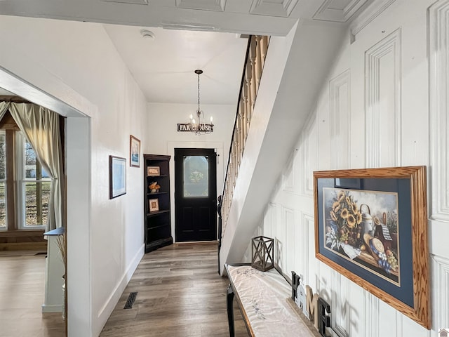 entryway with hardwood / wood-style floors and a notable chandelier