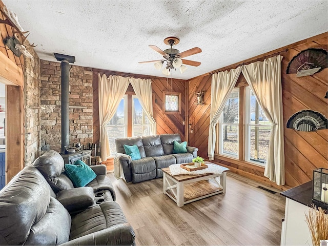 living room featuring plenty of natural light, light hardwood / wood-style floors, a wood stove, and a textured ceiling