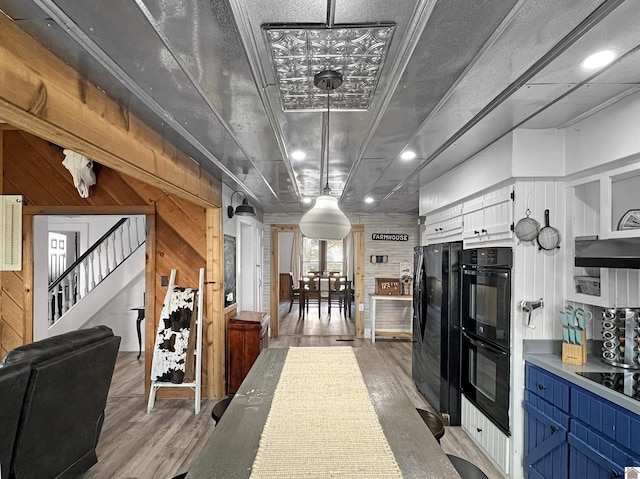 kitchen featuring decorative light fixtures, black appliances, and wood walls