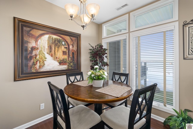 dining area featuring a notable chandelier, a healthy amount of sunlight, and dark wood-type flooring