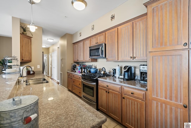 kitchen with pendant lighting, sink, light stone countertops, and stainless steel appliances