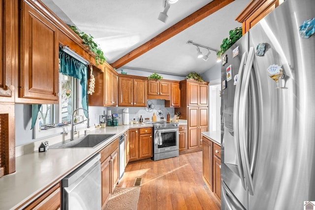 kitchen with track lighting, lofted ceiling with beams, sink, light wood-type flooring, and appliances with stainless steel finishes