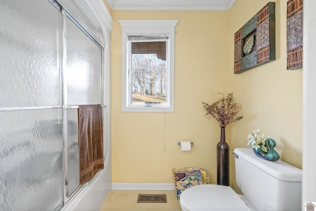 bathroom featuring toilet, crown molding, and enclosed tub / shower combo