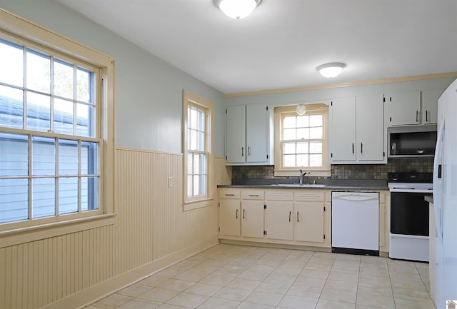 kitchen featuring light tile patterned floors, white appliances, plenty of natural light, and wood walls