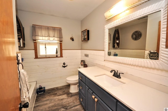 bathroom with vanity, wood-type flooring, toilet, a tub, and wood walls