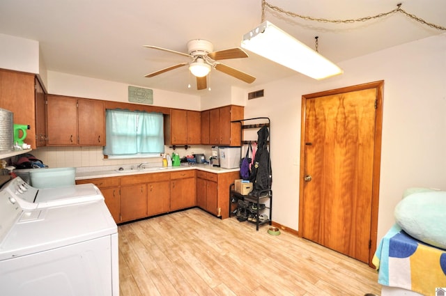 kitchen featuring ceiling fan, sink, tasteful backsplash, light hardwood / wood-style flooring, and washer and clothes dryer