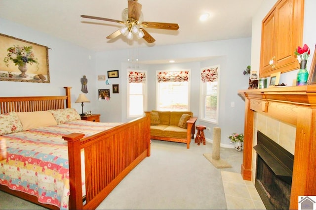 bedroom with ceiling fan, light colored carpet, and a fireplace