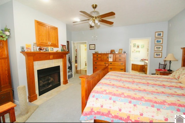 carpeted bedroom with connected bathroom, ceiling fan, and a tile fireplace