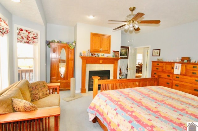 carpeted bedroom with a tile fireplace and ceiling fan