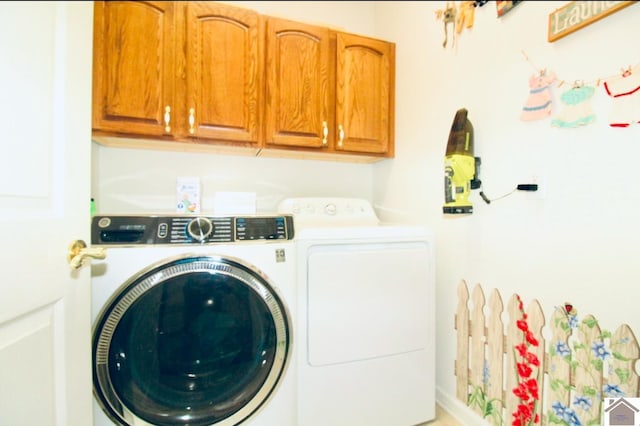 clothes washing area featuring washer and clothes dryer and cabinets