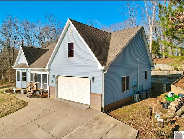 view of side of property featuring central AC, a garage, and a sunroom