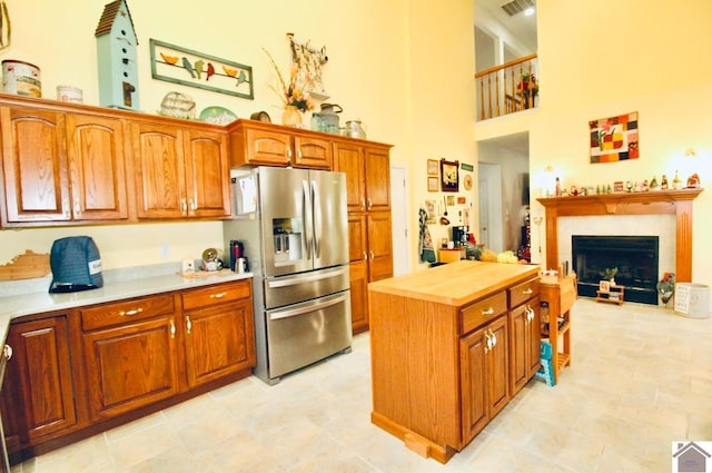 kitchen with butcher block counters, stainless steel fridge with ice dispenser, a center island, and a towering ceiling