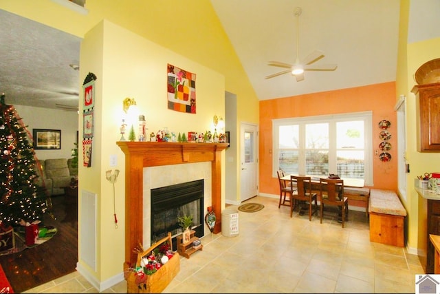 living room with light tile patterned floors, high vaulted ceiling, ceiling fan, and a tiled fireplace