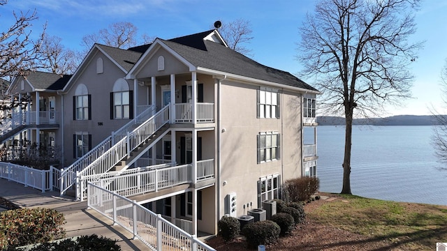 rear view of house with central AC unit and a water view