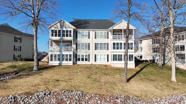 rear view of property featuring a lawn and a balcony