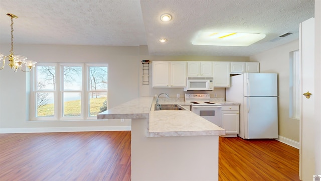 kitchen with kitchen peninsula, a textured ceiling, decorative light fixtures, white appliances, and light wood-type flooring