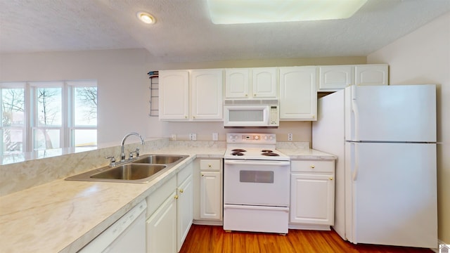 kitchen featuring white cabinetry, sink, white appliances, and light hardwood / wood-style flooring