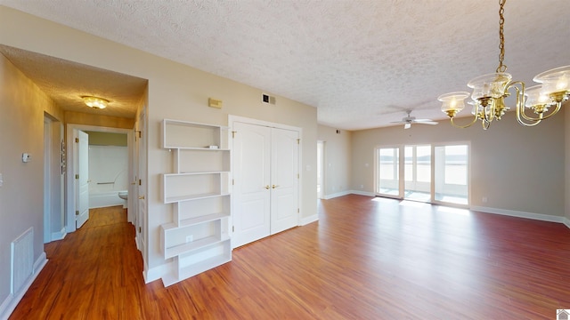 spare room with a textured ceiling, ceiling fan with notable chandelier, and hardwood / wood-style flooring