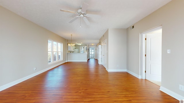 unfurnished living room with hardwood / wood-style floors, ceiling fan with notable chandelier, and a textured ceiling