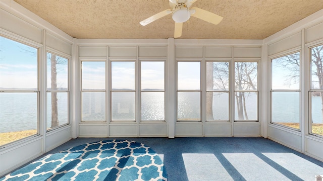 unfurnished sunroom with ceiling fan and a water view