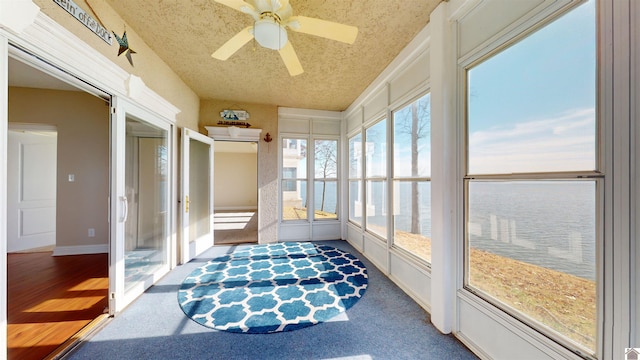 sunroom / solarium with a water view and ceiling fan