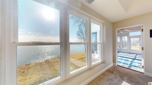 doorway featuring ceiling fan, a water view, and carpet floors