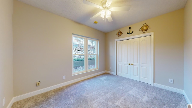 unfurnished bedroom with a textured ceiling, carpet floors, a closet, and ceiling fan