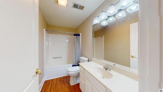 full bathroom featuring wood-type flooring, a textured ceiling, toilet, shower / tub combo with curtain, and vanity