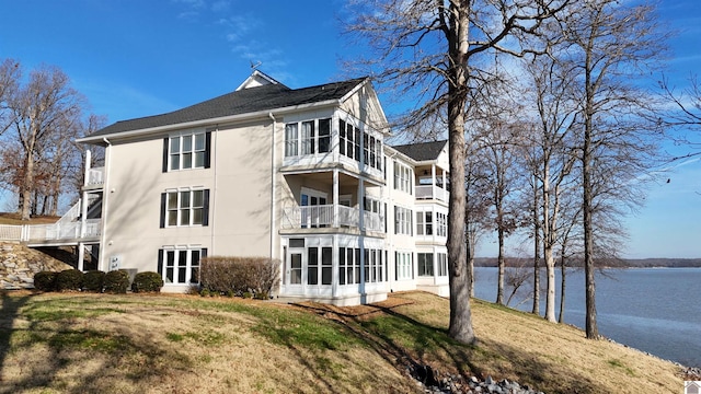 back of property featuring a lawn, a water view, and a balcony