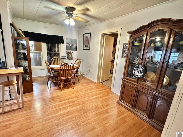 dining area with ceiling fan, a fireplace, and light hardwood / wood-style flooring