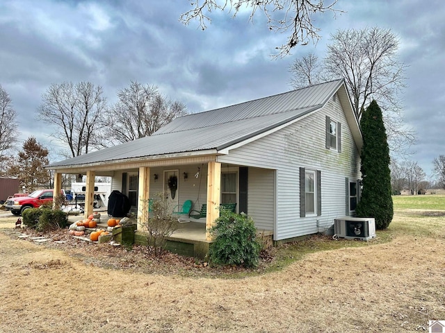 view of front of property featuring a porch, central air condition unit, and a front lawn