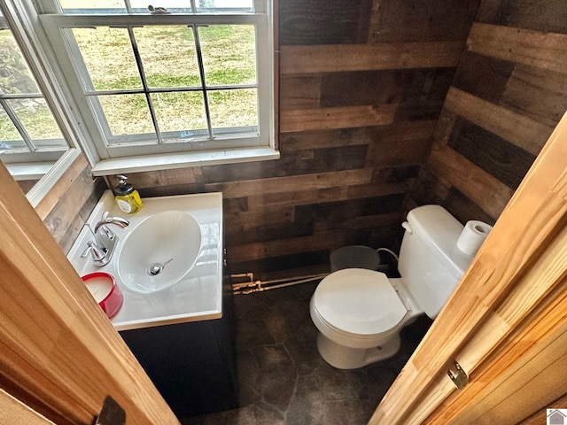 bathroom with vanity, toilet, and wooden walls