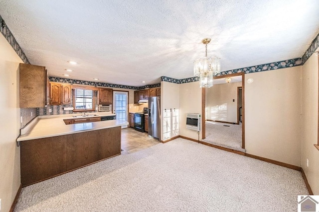 kitchen with pendant lighting, black appliances, a notable chandelier, kitchen peninsula, and heating unit